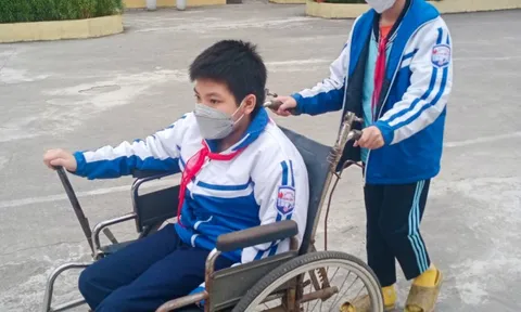 Cậu bé bốn năm đẩy xe lăn đưa bạn đến trường